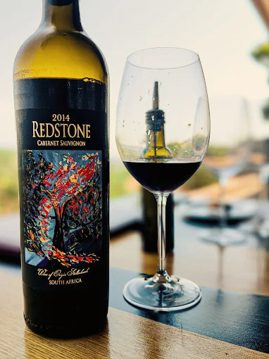 A bottle of 2014 Redstone Cabernet Sauvignon next to a glass of red
