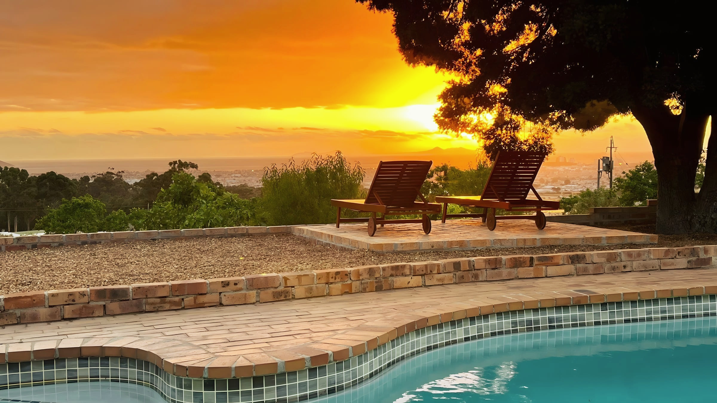 Sunset over the pool and the loungers beneath the milkwood